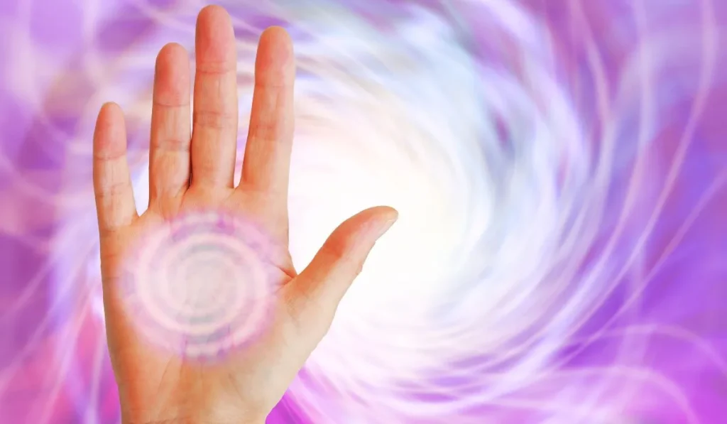Dłoń Mistrza Reiki na tle fioletowych kosmicznych energii